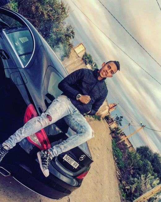 Soufiane Rahimi sitting on his Mercedes Benz